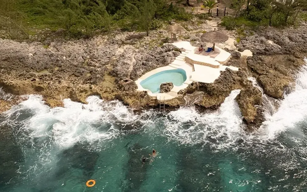 Aerial view of the oceanfront retreat with a pool and rocky coastline